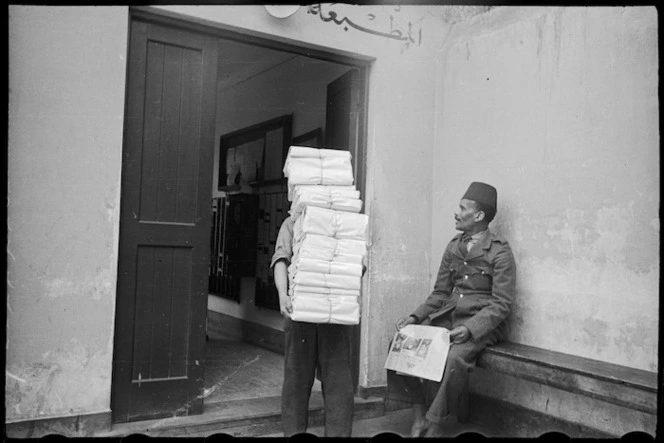 Porter carries bundles of the NZEF Times to truck for transportation, Egypt, World War II - Photograph taken by George Bull