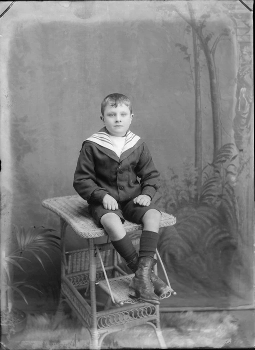 Studio family unidentified family portrait of a young boy in a sailor's outfit sitting on a cane table, Christchurch