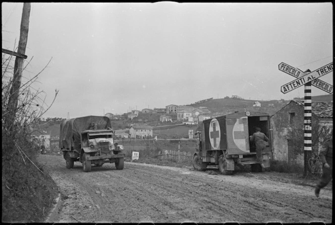 Vehicles of 2 NZ Divison near a railway crossing on road near Italian Front lines, World War II - Photograph taken by George Kaye