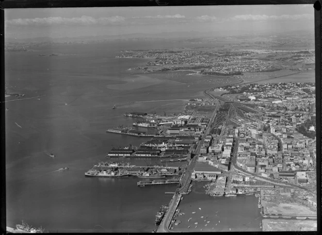 Ports of Auckland wharves and city centre with railway yards, with Tamaki Drive Bridge and the Royal Akarana Yacht Club Marina beyond, Auckland City
