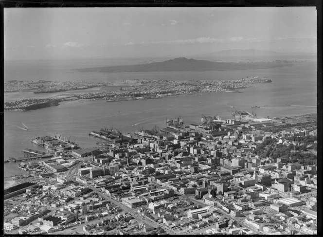 Auckland City with Nelson and Hobson Streets, Albert Park, railway yards, the dock area and harbour, with Devonport and Rangitoto Island beyond
