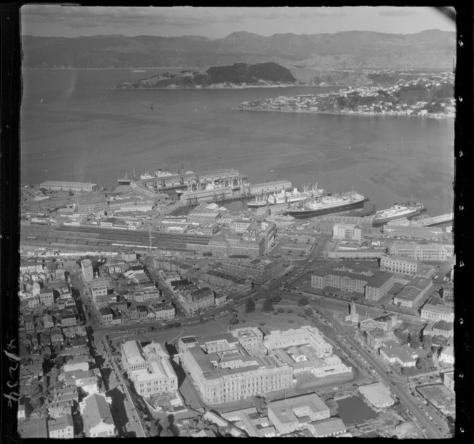 Wellington City with Parliament Buildings in foreground and Molesworth Street, with Government Building, Wellington Railway Station, wharves and harbour beyond