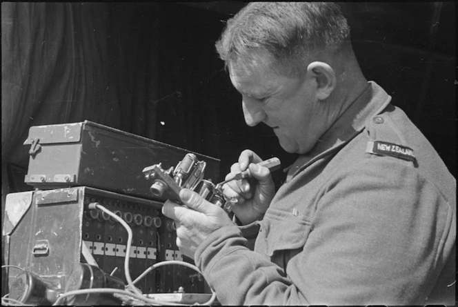 A B Smith adjusts an exchange relay on the Cassino Front in Italy, World War II - Photograph taken by George Kaye