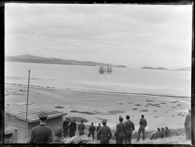 Members of the Royal New Zealand Air Force standing on a hill, watching rockets fire into the sea, Auckland