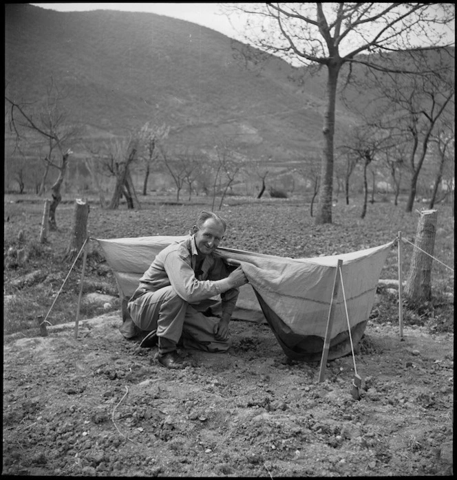 Staff Sergeant R R Rae showing mosquito-proof net to be issued to forward troops of 2 NZ Division in Italy, World War II - Photograph taken by M D Elias