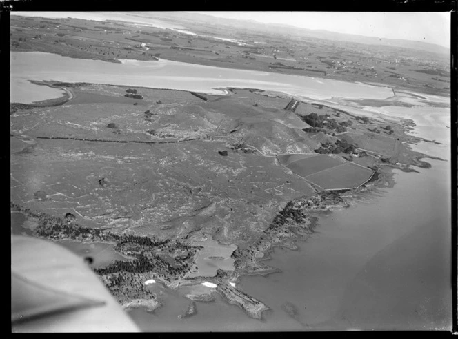 View of the Kellihers' Puketutu Island farm and road access causeway with Mangere and Manukau City beyond, Manukau Harbour, South Auckland