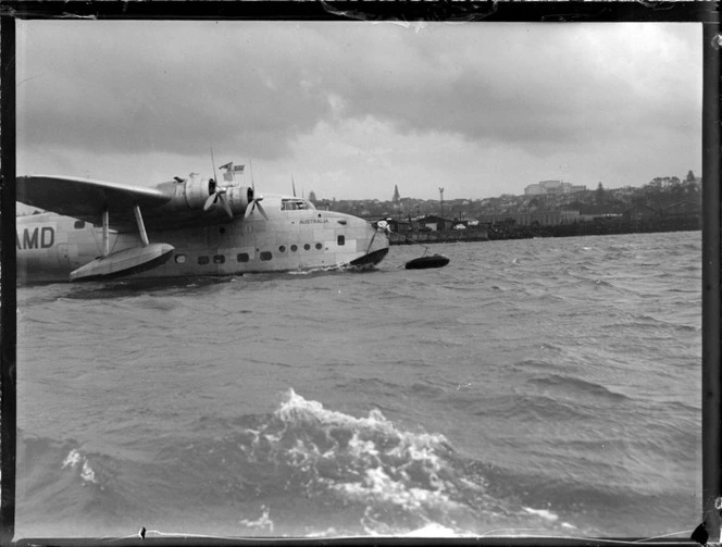 View of the TEAL Short Tasman Flying Boat ZK-AMD 'Australia' being hitched to a mooring with the help of an unidentified crew member, Mechanic's Bay, Auckland City