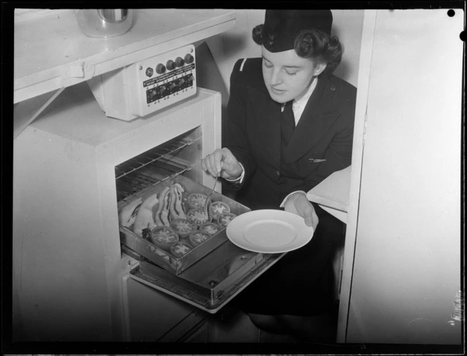 Tasman Empire Airways stewardess [Mrs Colley?] preparing bacon and tomatoes