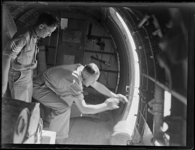 Interior of a Douglas Dakota aircraft, showing two unidentified men emptying drums from the cargo hold of the Dakota aircraft