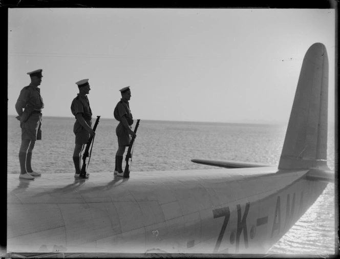 Group portrait of three unidentified RNZN soldiers at attention standing on top of TEAL Short S30 Empire Class flying boat 'Aotearoa' ZK-AMA, Suva, Fiji