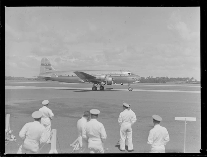 PAA NC-69883 Clipper Class Kathay four engine passenger plane taxiing on runway with unidentified ground staff watching, Whenuapai Airfield, Auckland