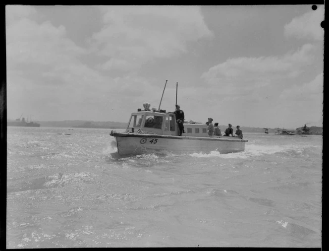 RNZAF (Royal New Zealand Air Force) passenger boat with RNZAF crew onboard heading to shore, background to the right is Short Sunderland flying boat Mataatua NZ4103, Mechanics Bay, Auckland