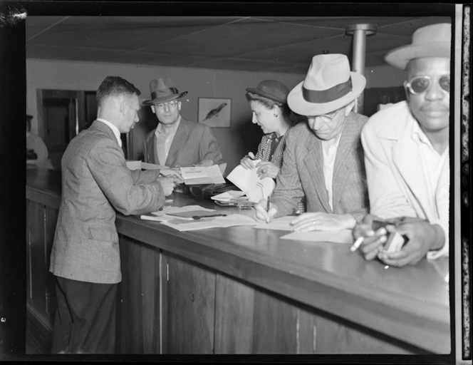 Passengers from PAWA (Pan American World Airways) clipper from America, showing an immigration official checking documents at Whenuapai airport, Auckland