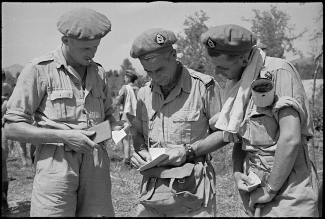 G S Kirk and T McKinnon consult 'Bookie' D J Commons before event at 24 NZ Battalion's boating carnival at Arce, Italy, World War II - Photograph taken by George Kaye