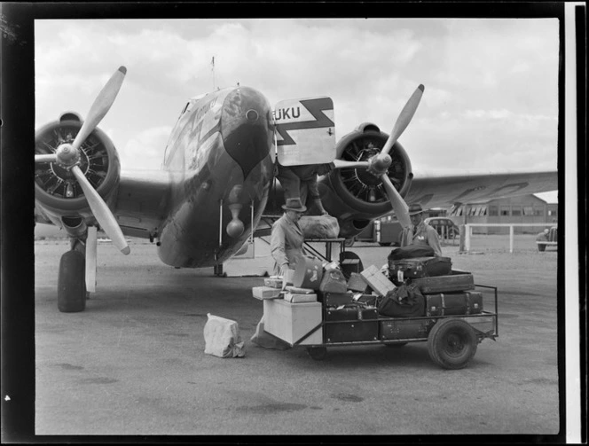 An unidentified man loading luggage onto New Zealand National Airways Corporation aeroplane 'Kotuku', location unidentified