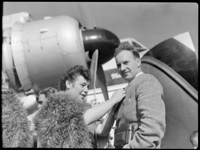 Bristol Freighter tour, Rotorua, showing Mr A E Davis receiving a poi brooch from Guide Bubbles, next to a Bristol Freighter aircraft