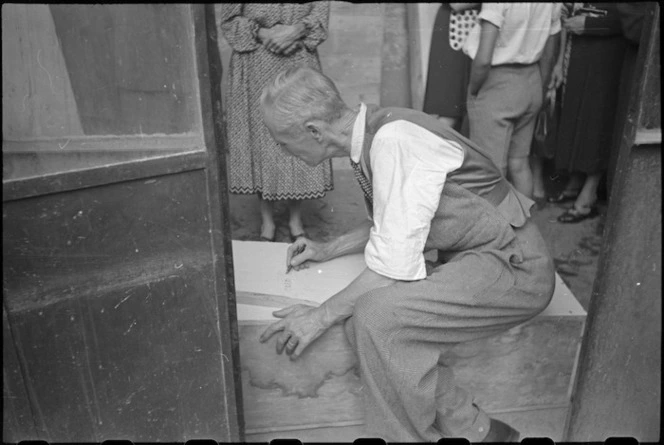 Italian civilian inscribing the name of German sniper victim on a coffin in Florence, Italy, World War II - Photograph taken by George Kaye