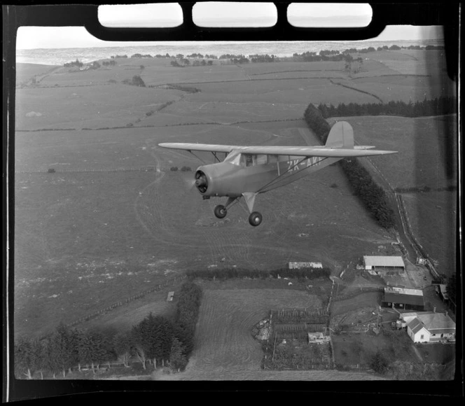 Rearwin Sportster aeroplane ZK-AKF, in flight over a rural area, Auckland Region