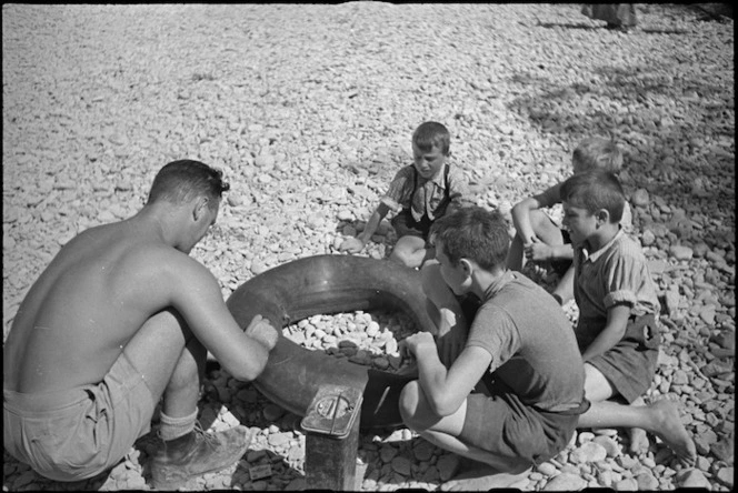 C L Carpenter repairs a tube in the dried up Pisa River bed near Florence, Italy, World War II - Photograph taken by George Kaye