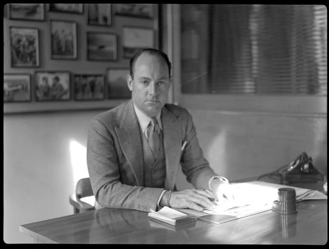 Portrait of Mr Whitney-Straight, sitting at a desk, during a BOAC (British Overseas Airways Corporation) visit to New Zealand, location unidentified