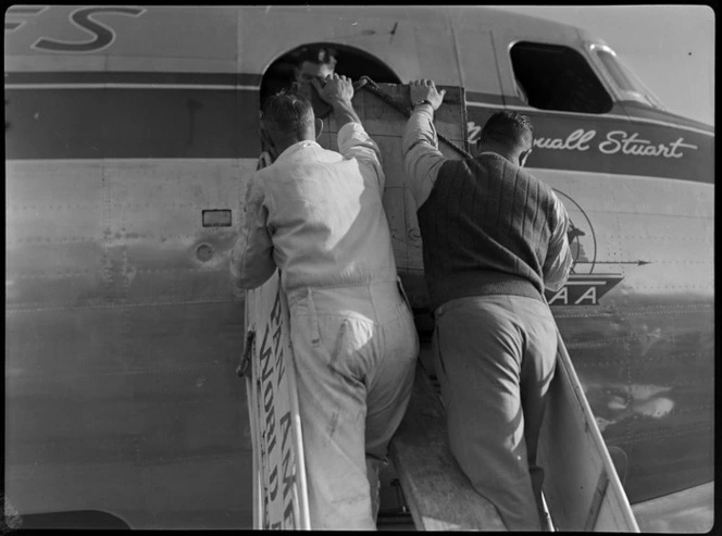 Airport ground crew unloading freight from aircraft McDouall Stuart, TAA (Trans Australia Airlines), at Whenuapai Air Base, Auckland