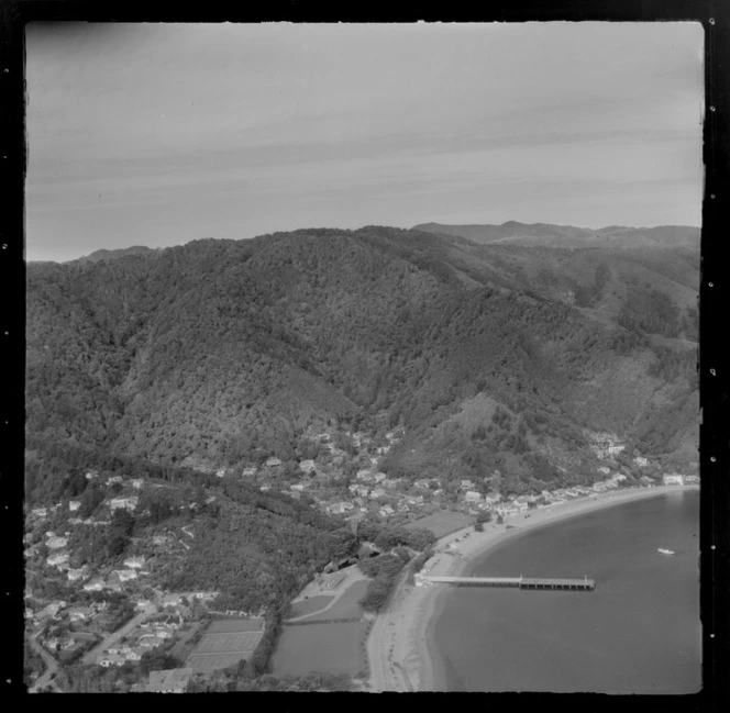 View over the Lower Hutt Valley suburb of Eastbourne with Days Bay Wharf and Pavilion with duck pond, with Wellesley College tennis courts and sports field in foreground, Wellington Harbour