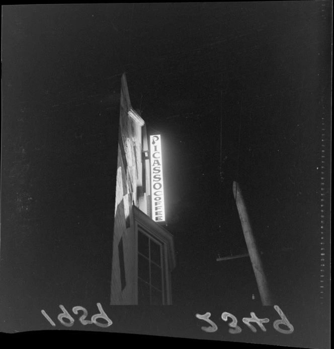Exterior view of a building at night, featuring a neon sign, reading 'Picasso Coffee', probably Wellington