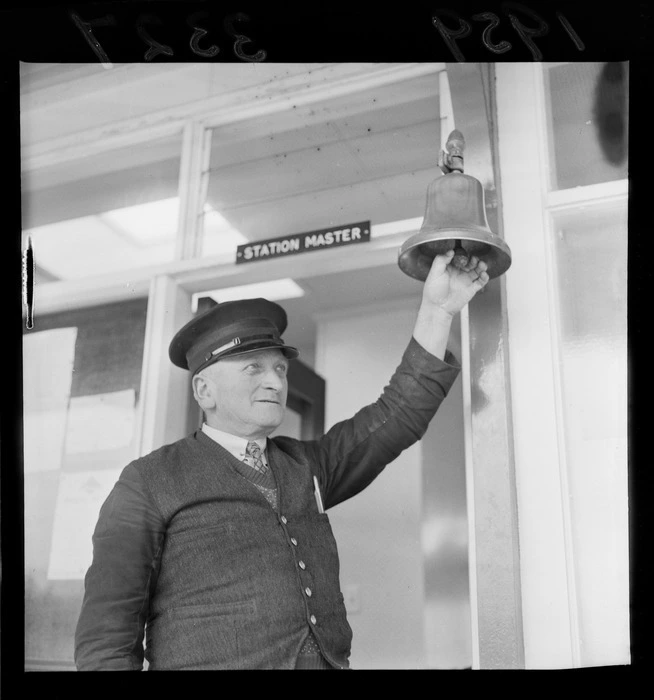 Mr Linklater, Stationmaster, ringing a train bell at Porirua, Wellington