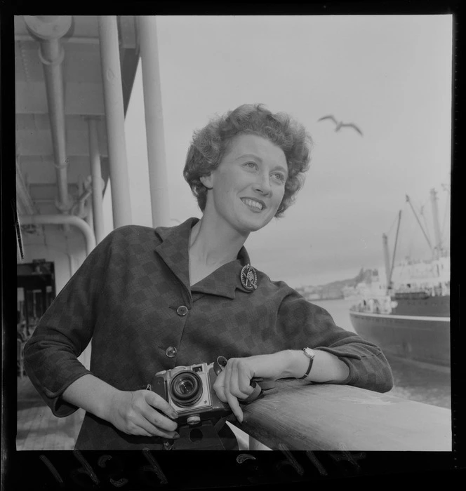 Portrait of Miss Erin O'Rourke holding a camera on the deck of a passenger boat, Wellington Harbour