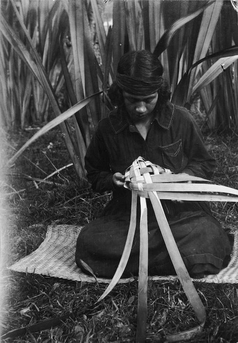 Woman weaving a food basket (rourou or kono) from flax leaves, at Koroniti