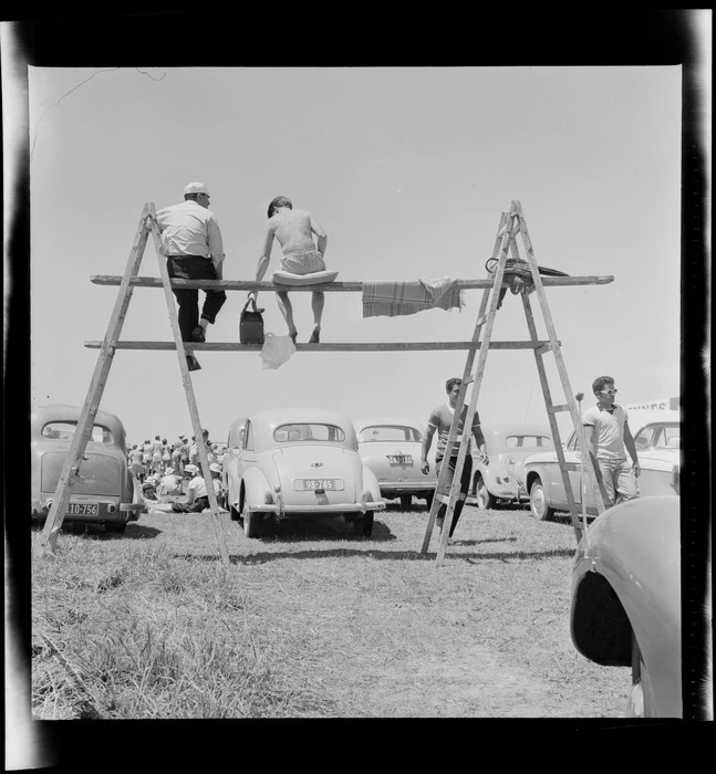 Men sitting on a make-shift scaffolding, watching race, at the New Zealand Grand Prix, Ardmore Airport, Manukau, Auckland
