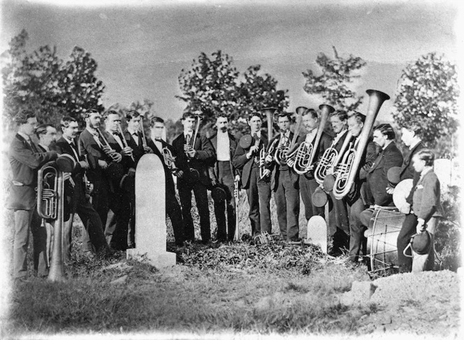 Members of a brass band gathered around a grave