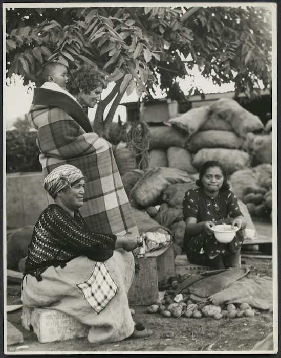 Three Maori women, one wrapped in a blanket with a baby on her back