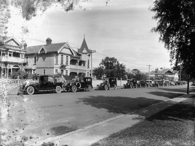 Hearse and other cars parked alongside houses on Latimer Square, Christchurch