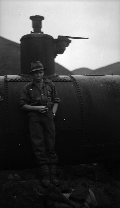 Man standing in front of old mining machinery, Terawhiti Station, Wellington