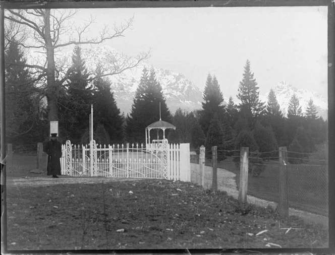 Lydia Williams in front of the gates of the Queenstown Peninsula Gardens and band rotunda with the snow covered Remarkable Mountains beyond, Queenstown, Central Otago Region