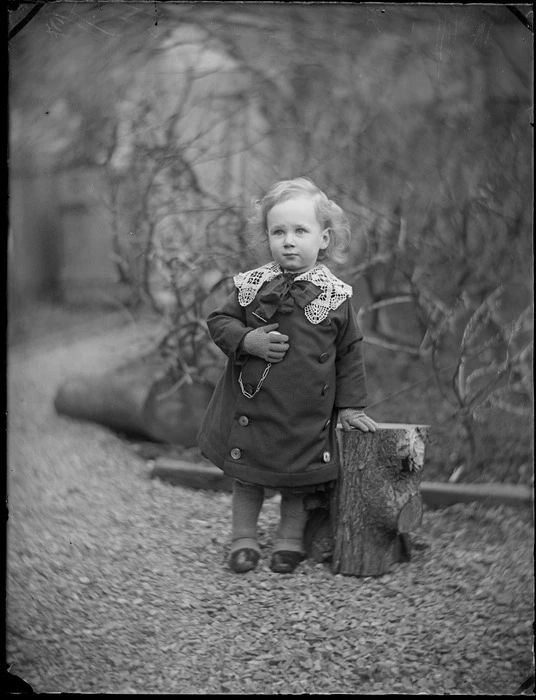 Portrait of a young Edgar Williams standing beside a log in the yard of the family house, 'View Bank', Maitland Street, Dunedin