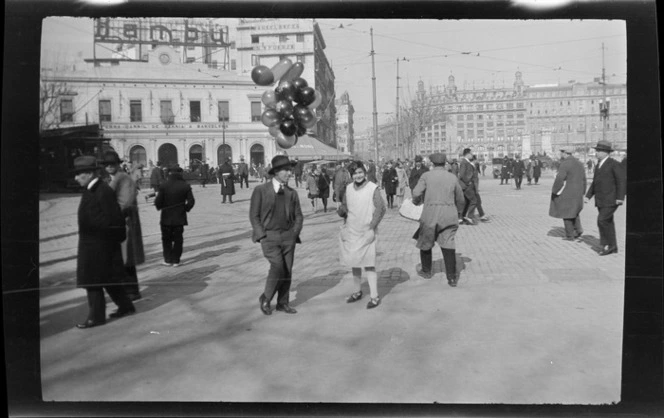 Pedestrians and balloon sellers in city plaza, including buildings in the background, Barcelona, Spain