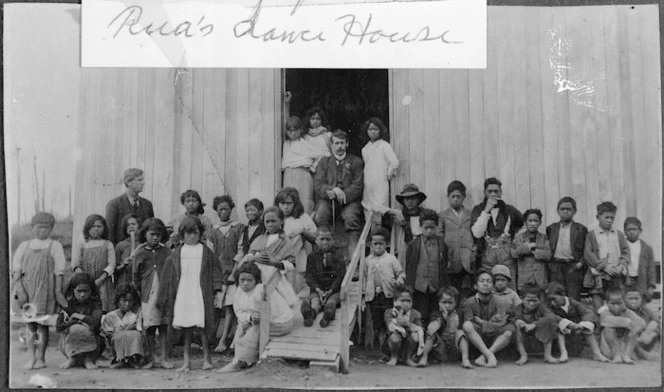 Reverend John George Laughton, his assistant John Currie, and their class of Maori children, outside Maungapohatu School