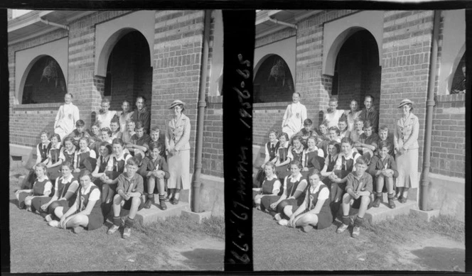Group of unidentified boys and girls, winners at a school sports day, sitting on steps of brick building, with two unidentified adults, Westport Technical High School, West Coast Region