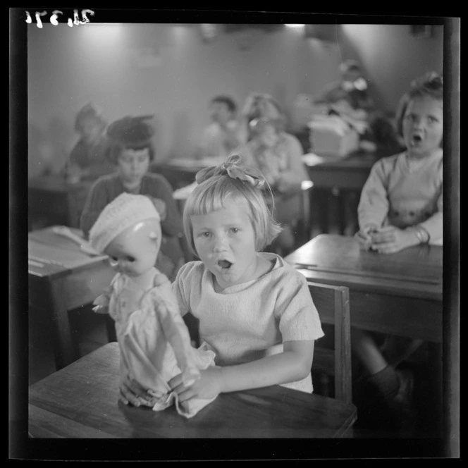 A young girl holds a doll in a classroom at a Polish refugee camp, Pahiatua