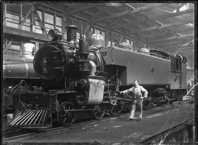 Albert Percy Godber standing beside a Wab class locomotive, NZR number 686, in the Petone Railway Workshops.