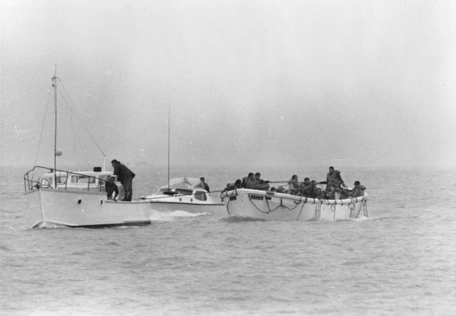 Survivors from the Wahine shipwreck in a lifeboat, being tugged by two boats, Wellington