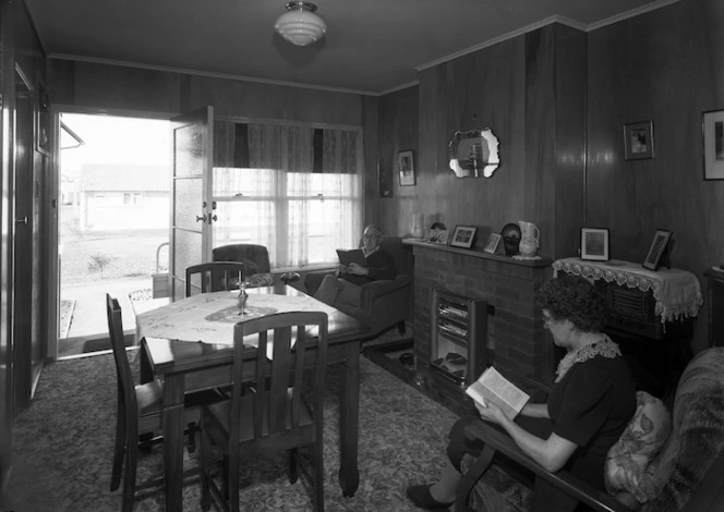 Pensioner's flat with man and woman sitting by the fireplace reading