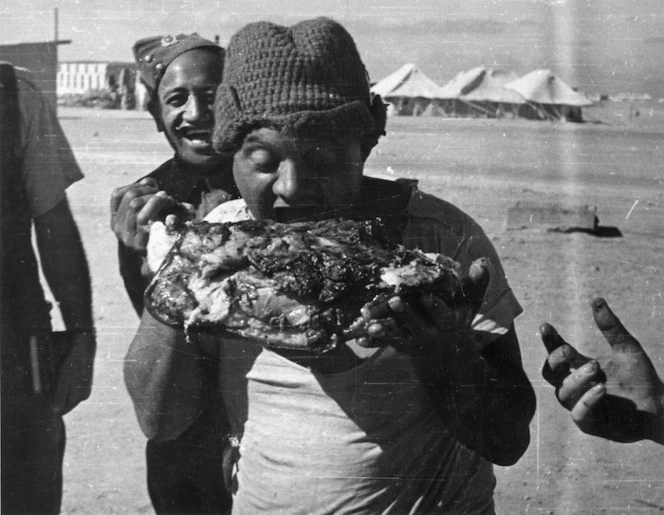 Soldier R White with a leg of pork from the hangi at the Maori Training Depot, Maadi, Christmas Day