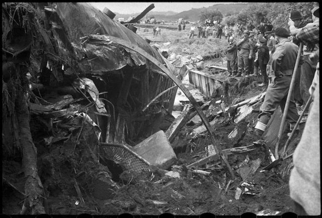 Group alongside a wrecked carriage at the scene of the railway disaster at Tangiwai
