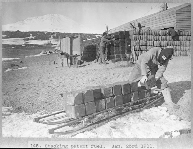 Members of the British Antarctic Expedition of 1911-1913 stacking coal briquettes alongside their hut in Antarctica