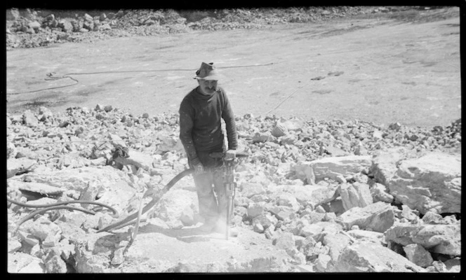 Man with pneumatic drill breaking limestone at cement works, Tarakohe