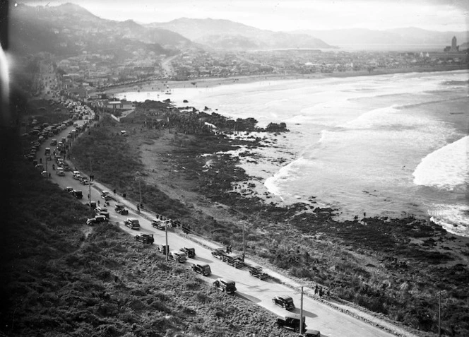 View over Lyall Bay, Wellington, showing a road congested with cars and a crowd of people whale watching on the waterfront