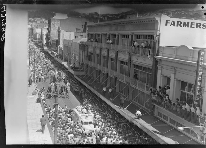 Crowds watching Cuba Street parade, Wellington, including elephants, outside Farmers and Woolworths buildings